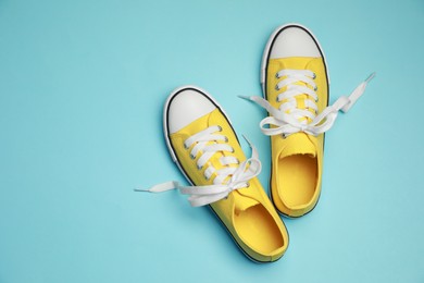 Pair of yellow classic old school sneakers on light blue background, flat lay. Space for text