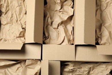 Photo of Open cardboard boxes with crumpled paper, top view. Packaging goods
