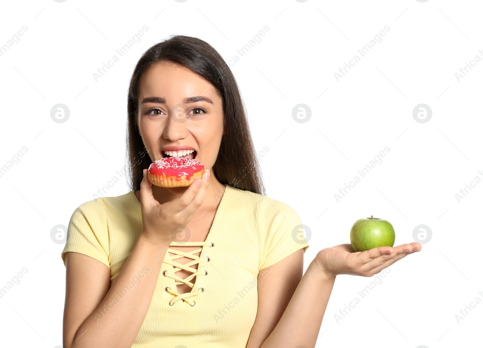 Photo of Concept of choice. Woman eating doughnut and holding apple on white background