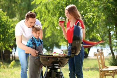 Happy family having barbecue with modern grill outdoors