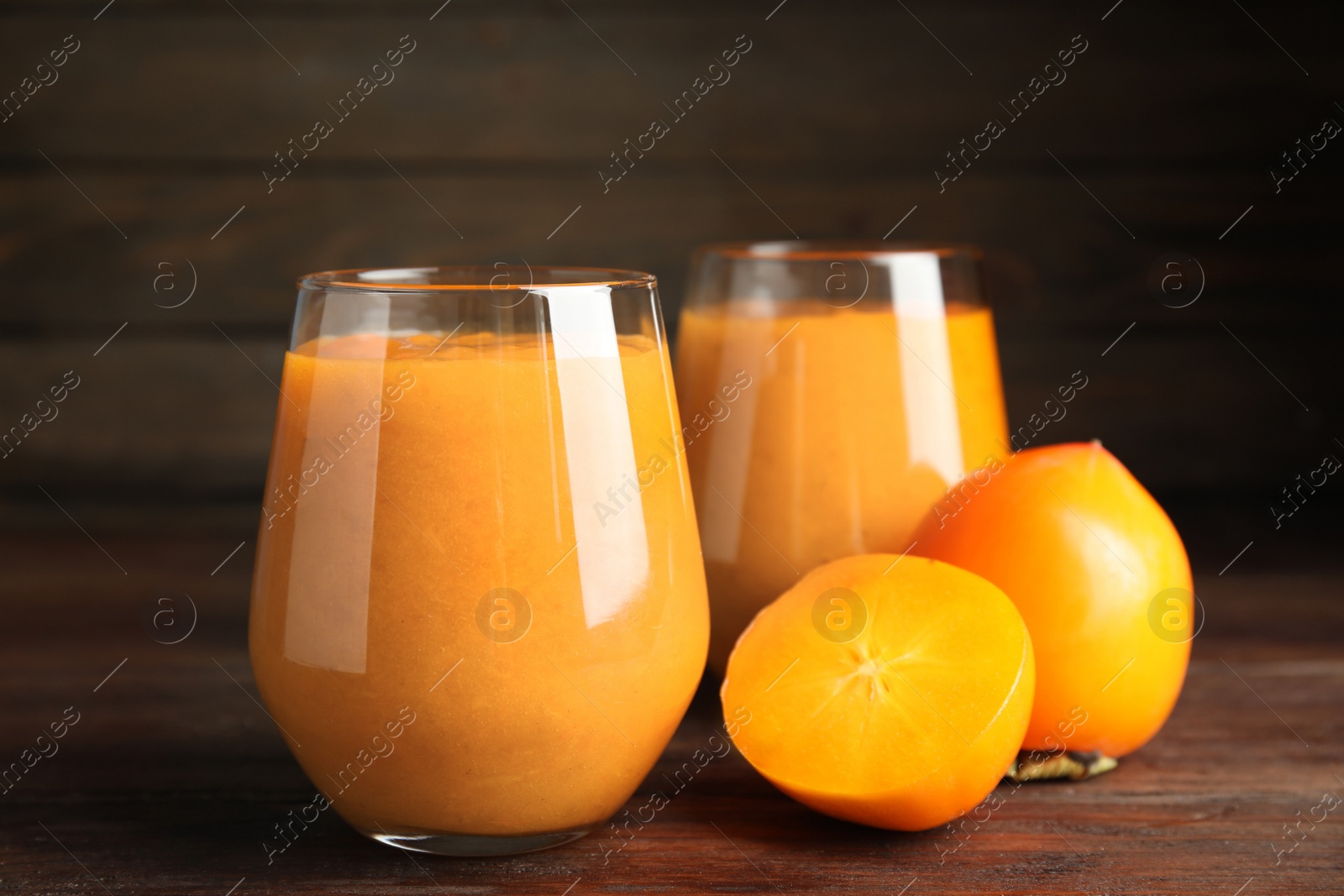 Photo of Tasty persimmon smoothie and fresh fruits on wooden table, closeup