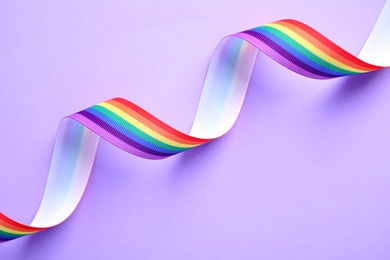 Photo of Bright rainbow ribbon on color background, top view. Symbol of gay community