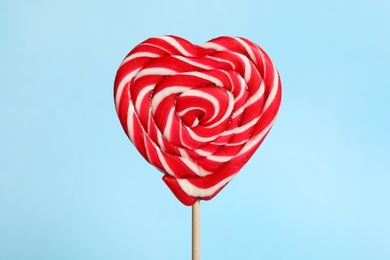 Photo of Sweet heart shaped lollipop on light blue background, closeup. Valentine's day celebration