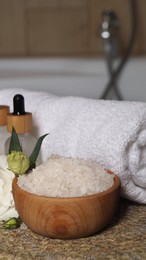 Photo of Bowl with bath salt and cosmetic product near fluffy towel on wicker mat indoors