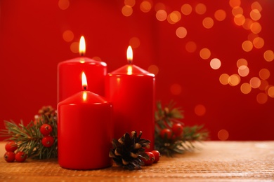 Beautiful Christmas composition with burning candles on wooden table against blurred lights. Space for text