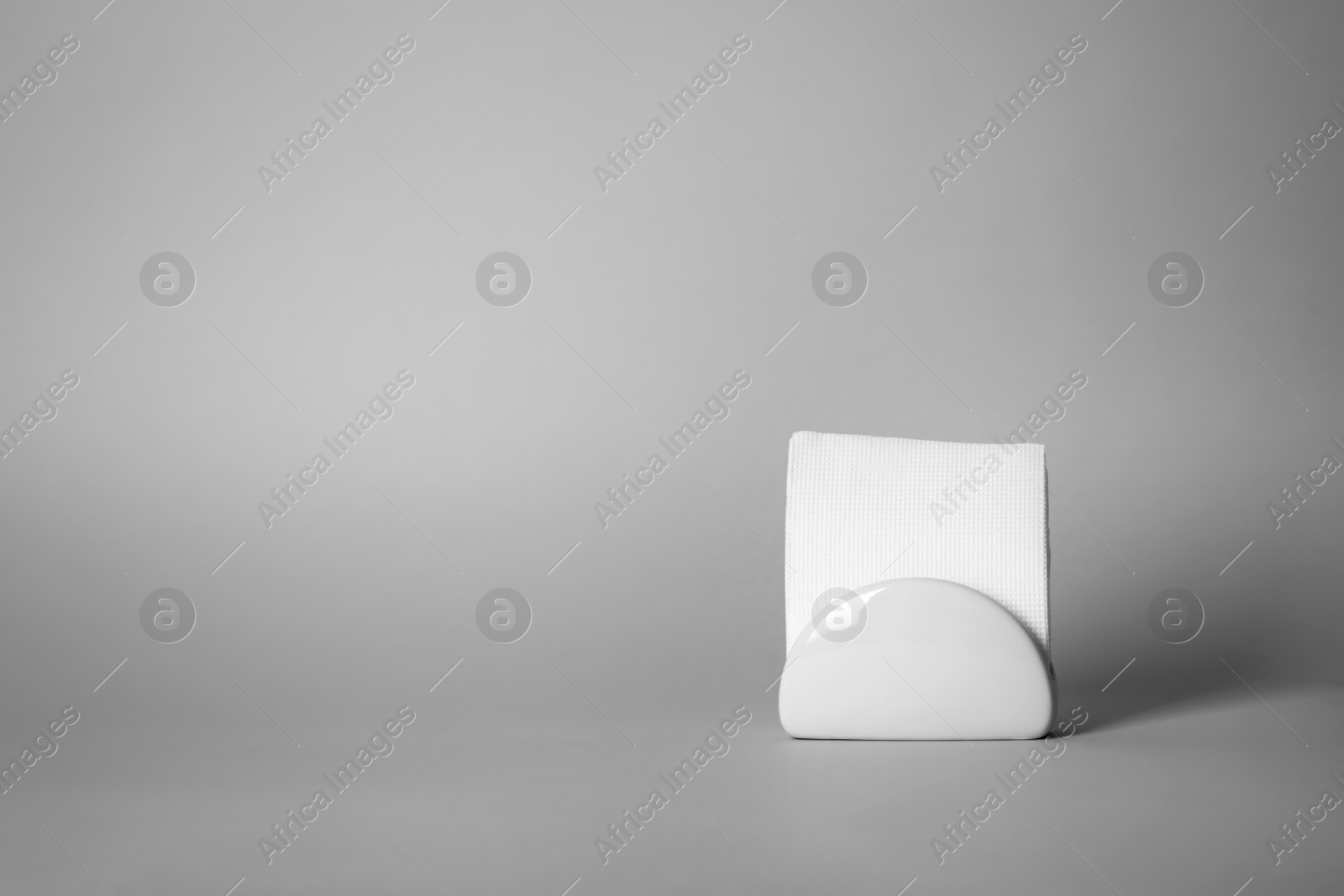 Photo of Napkin holder with paper serviettes on gray background. Space for text