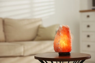 Himalayan salt lamp on table at home, space for text