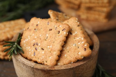 Cereal crackers with flax, sesame seeds and rosemary in bowl on table, closeup