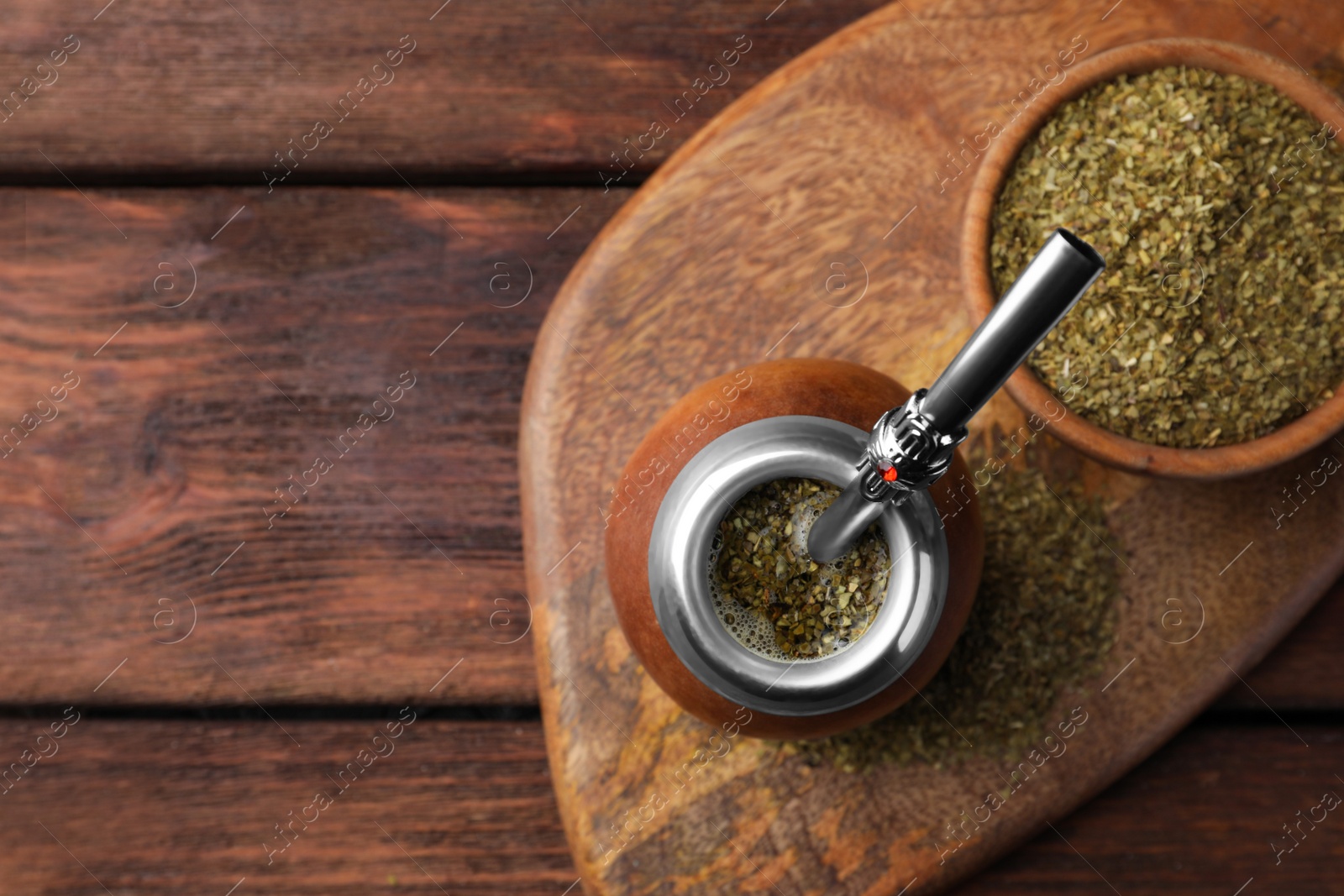 Photo of Calabash with mate tea and bombilla on wooden table, top view. Space for text