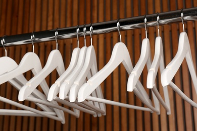 Photo of Empty hangers on rail against wooden background