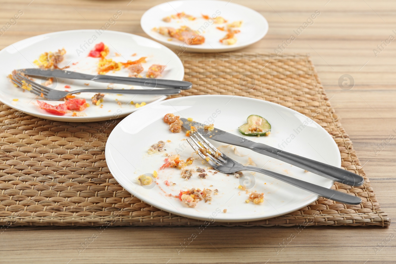 Photo of Dirty plates with leftovers on wooden table after party