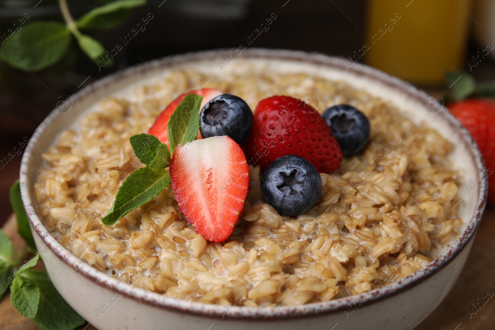 Photo of Tasty oatmeal with strawberries and blueberries in bowl on table, closeup