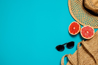 Photo of Beach bag, sunglasses, hat and grapefruit on light blue background, flat lay. Space for text
