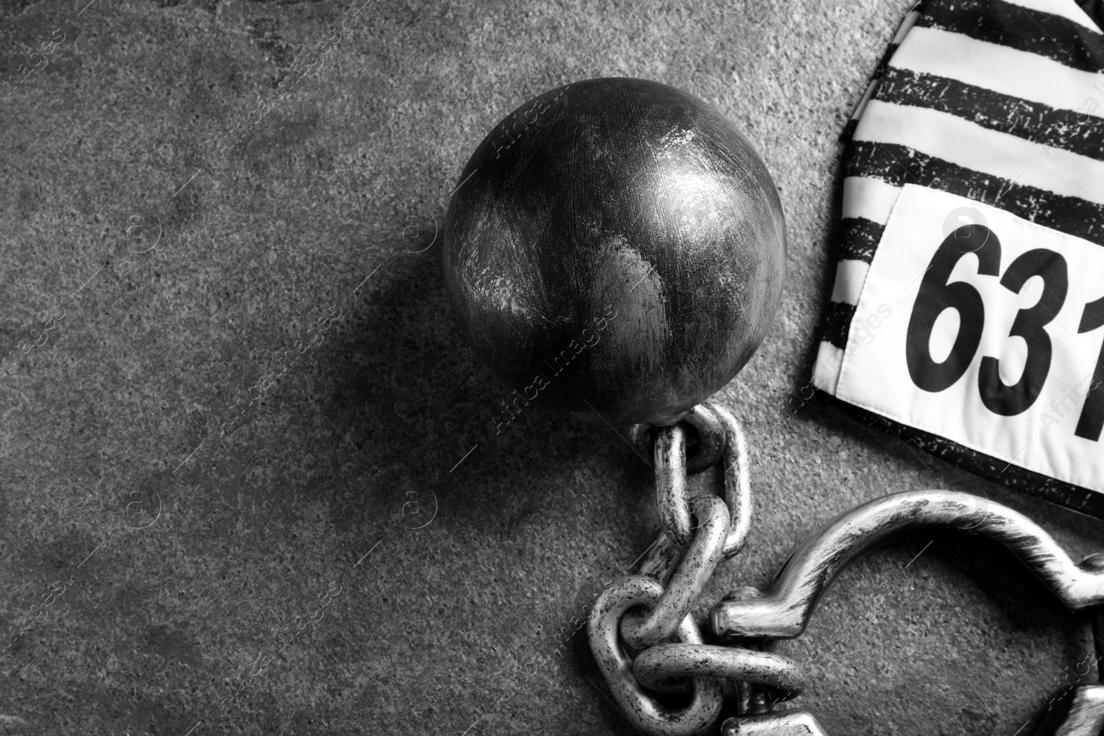 Photo of Prisoner ball with chain and jail clothes on grey table, flat lay. Space for text