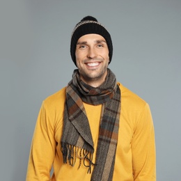 Photo of Happy young man in warm clothes on grey background. Winter season