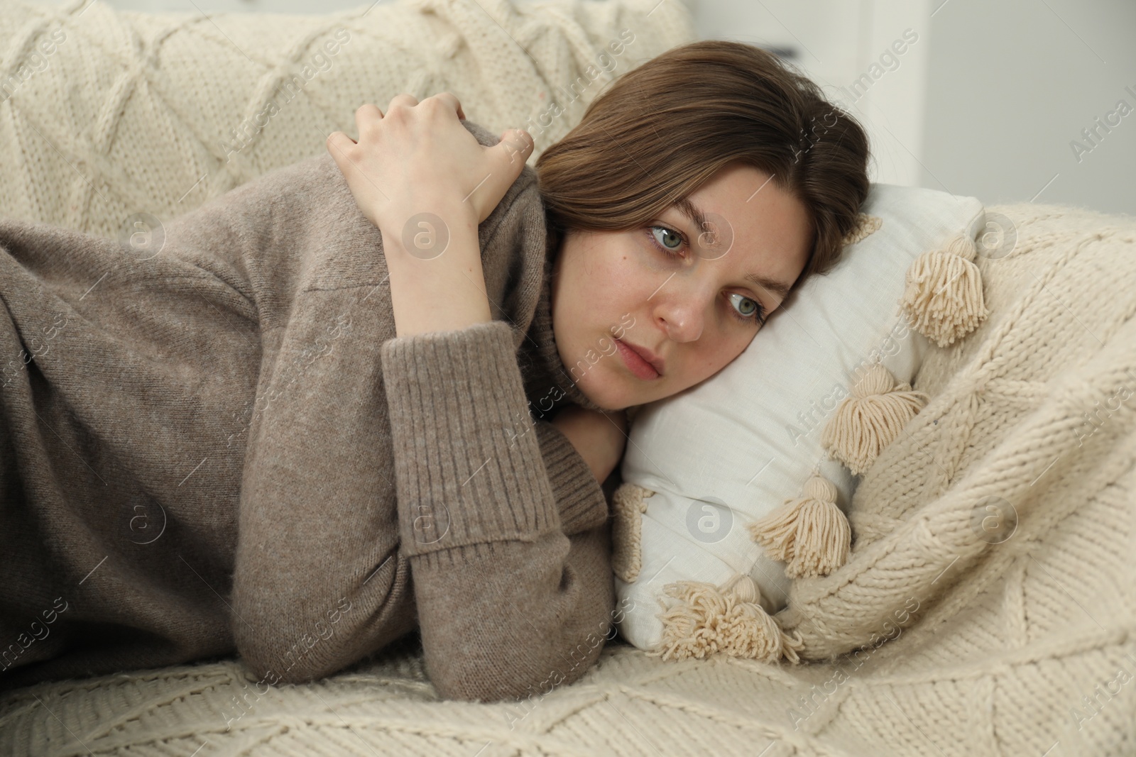 Photo of Sad young woman lying on sofa at home