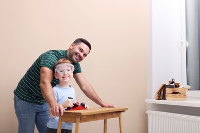 Photo of Father teaching son how to work with plane indoors