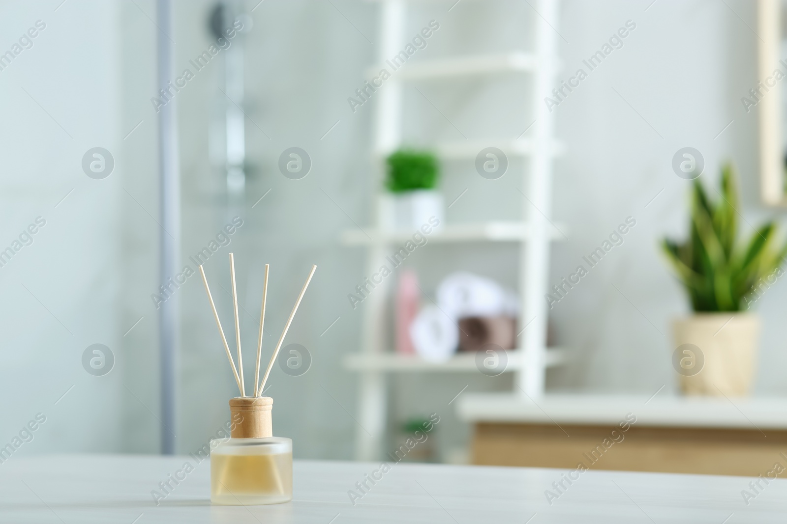 Photo of Aromatic reed air freshener on table indoors. Space for text