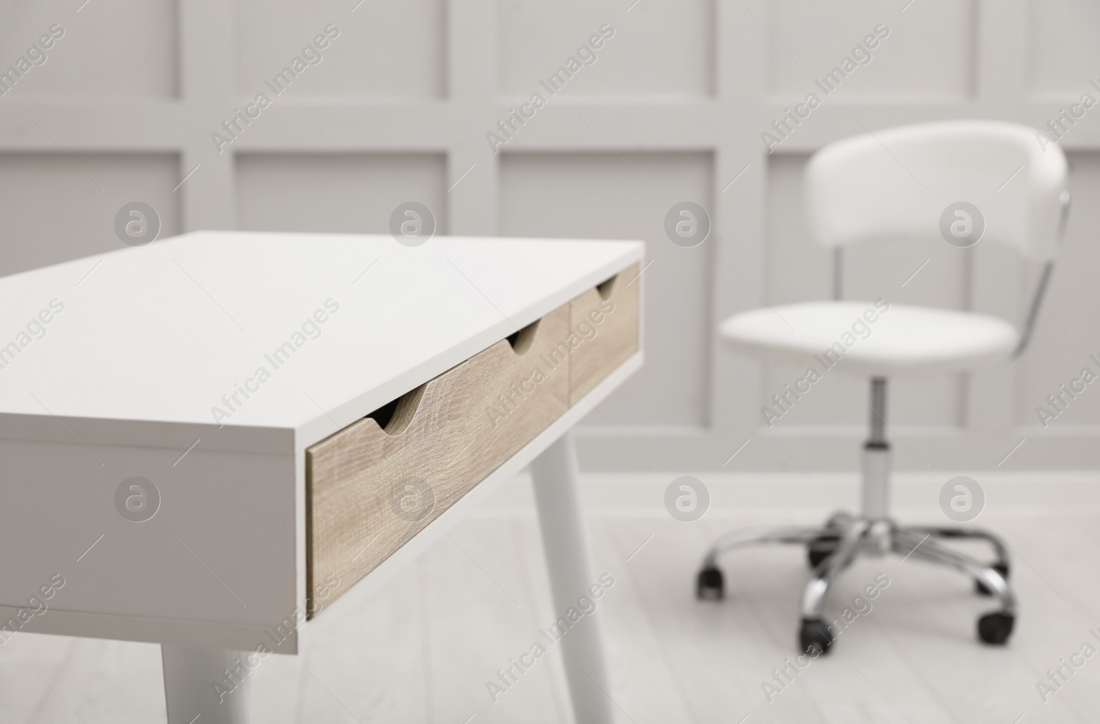 Photo of Modern white table with office chair indoors, closeup. Space for text