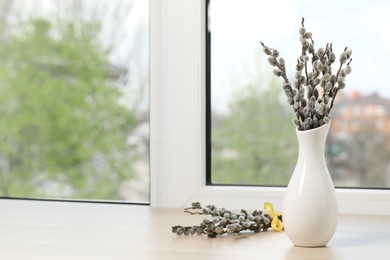 Beautiful pussy willow branches on window sill indoors, space for text