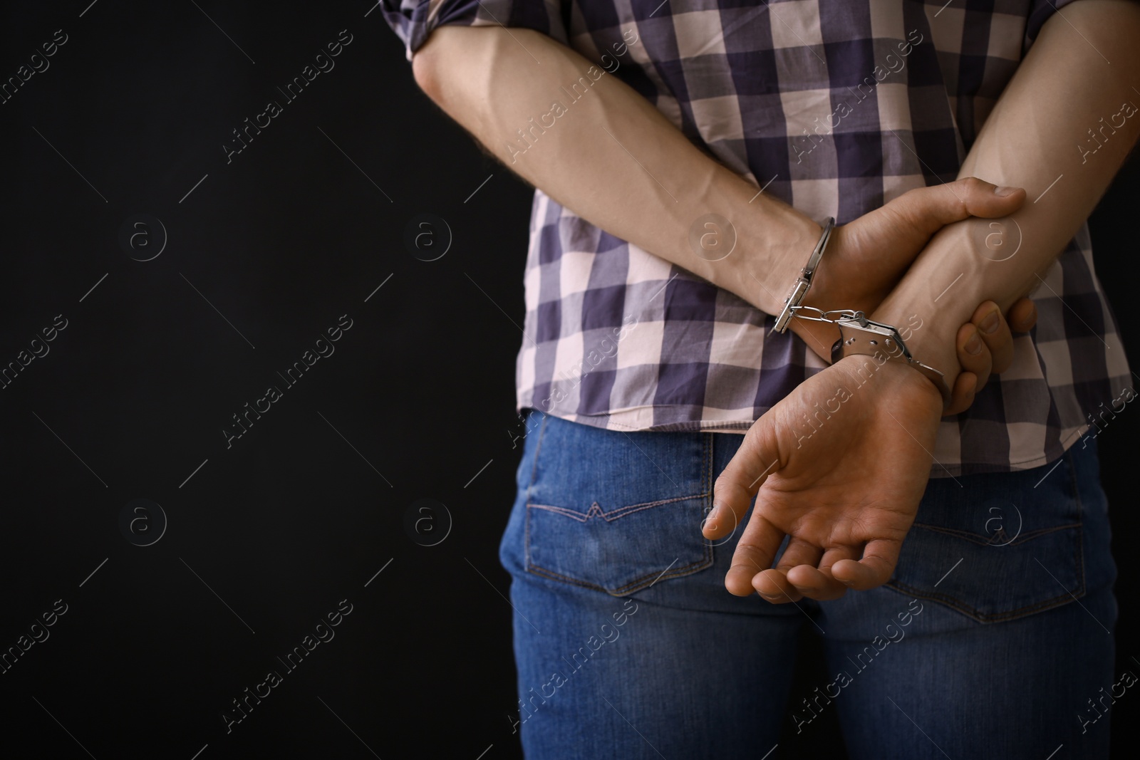 Photo of Man detained in handcuffs against dark background, space for text. Criminal law