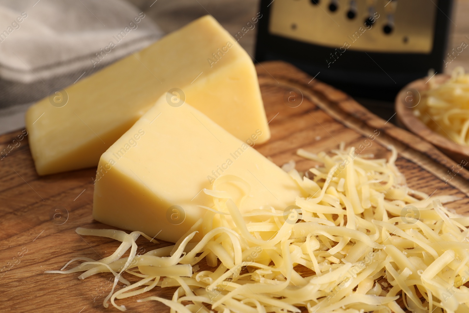 Photo of Grated and whole pieces of cheese on wooden table, closeup