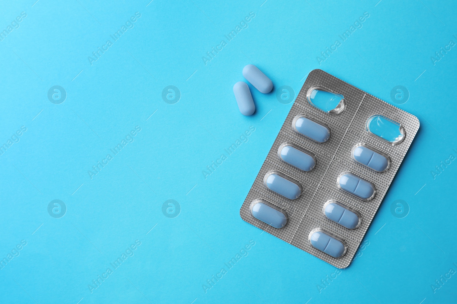 Photo of Pills and space for text on light blue background, top view. Potency problem