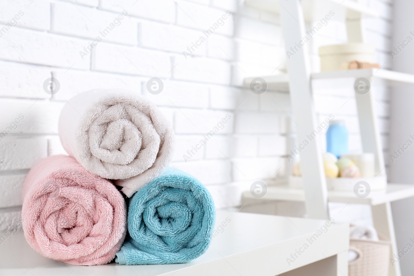 Photo of Rolled fresh towels on table in bathroom. Space for text