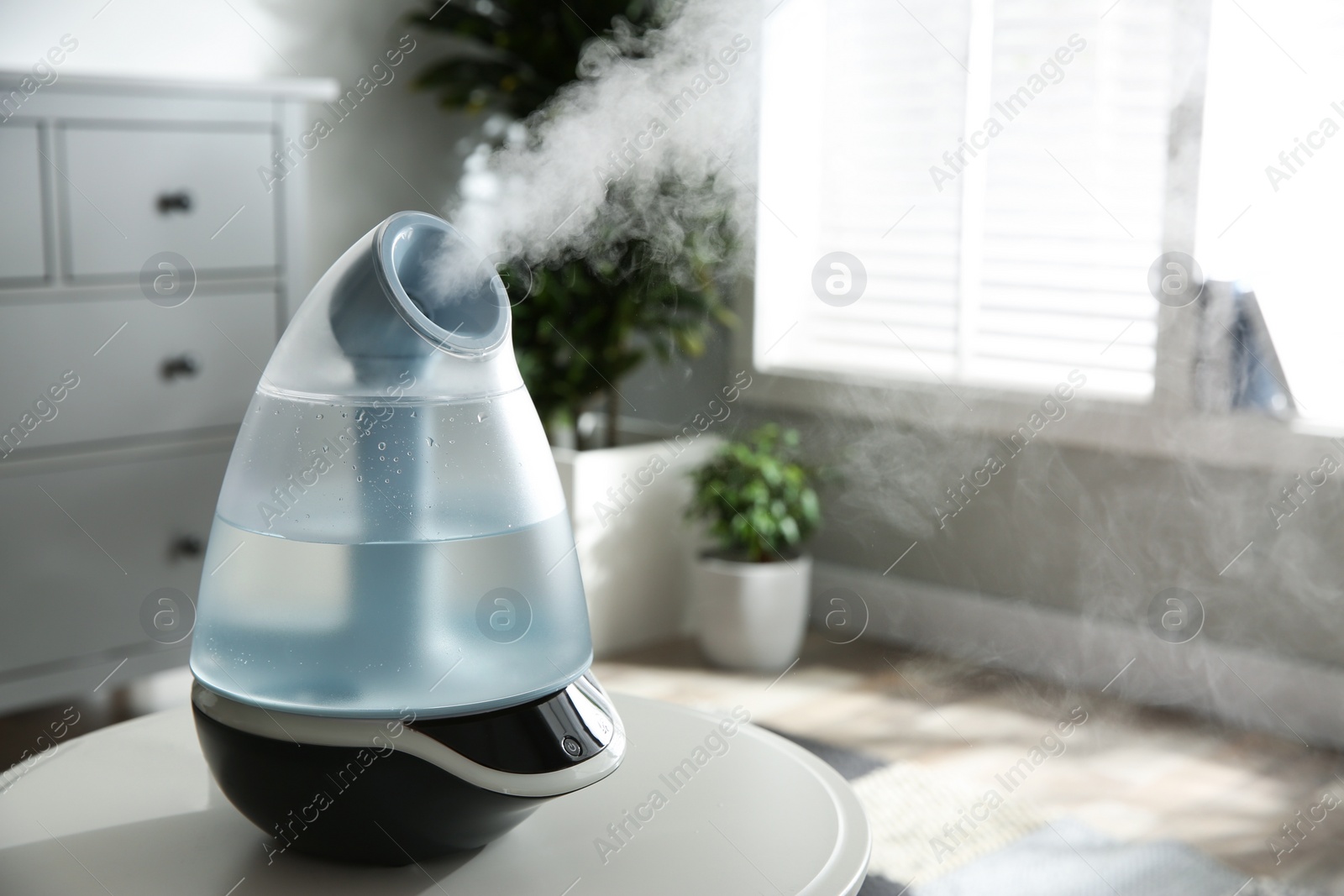 Photo of Modern air humidifier on table indoors. Space for text