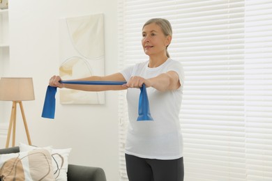 Photo of Senior woman doing exercise with fitness elastic band at home