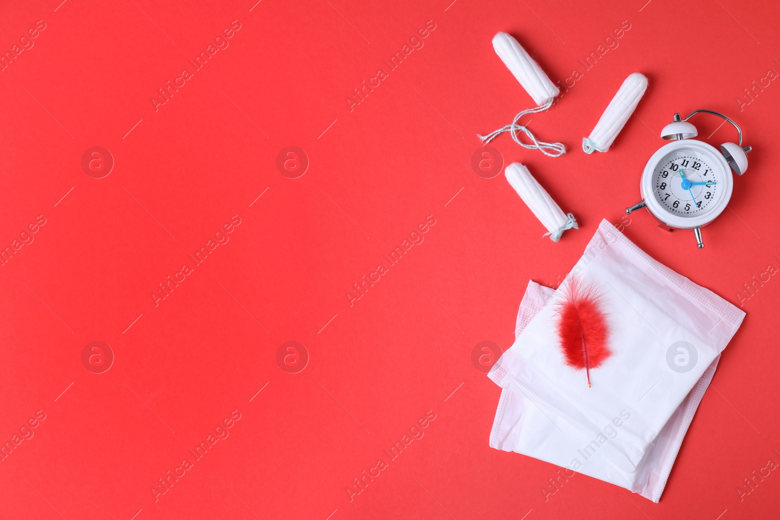 Photo of Different feminine hygiene products, alarm clock and red feather on color background, flat lay with space for text. Gynecological care