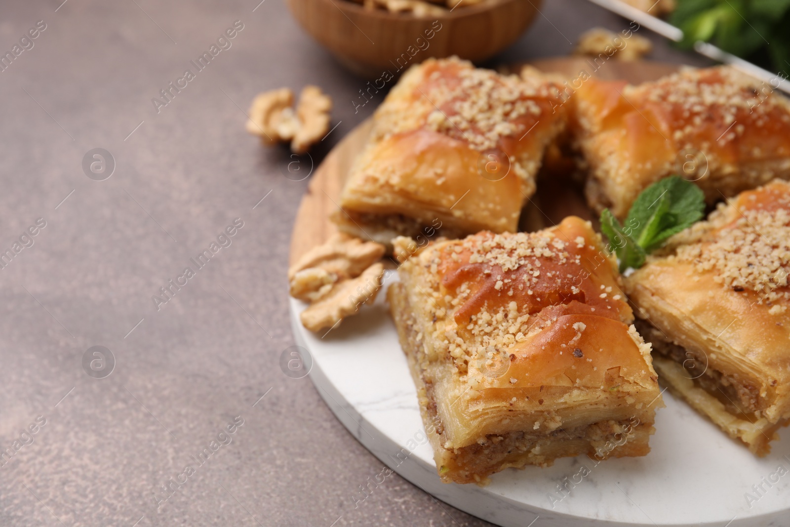 Photo of Eastern sweets. Pieces of tasty baklava on brown table, closeup. Space for text