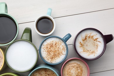 Many different cups with aromatic hot coffee on white wooden table, flat lay