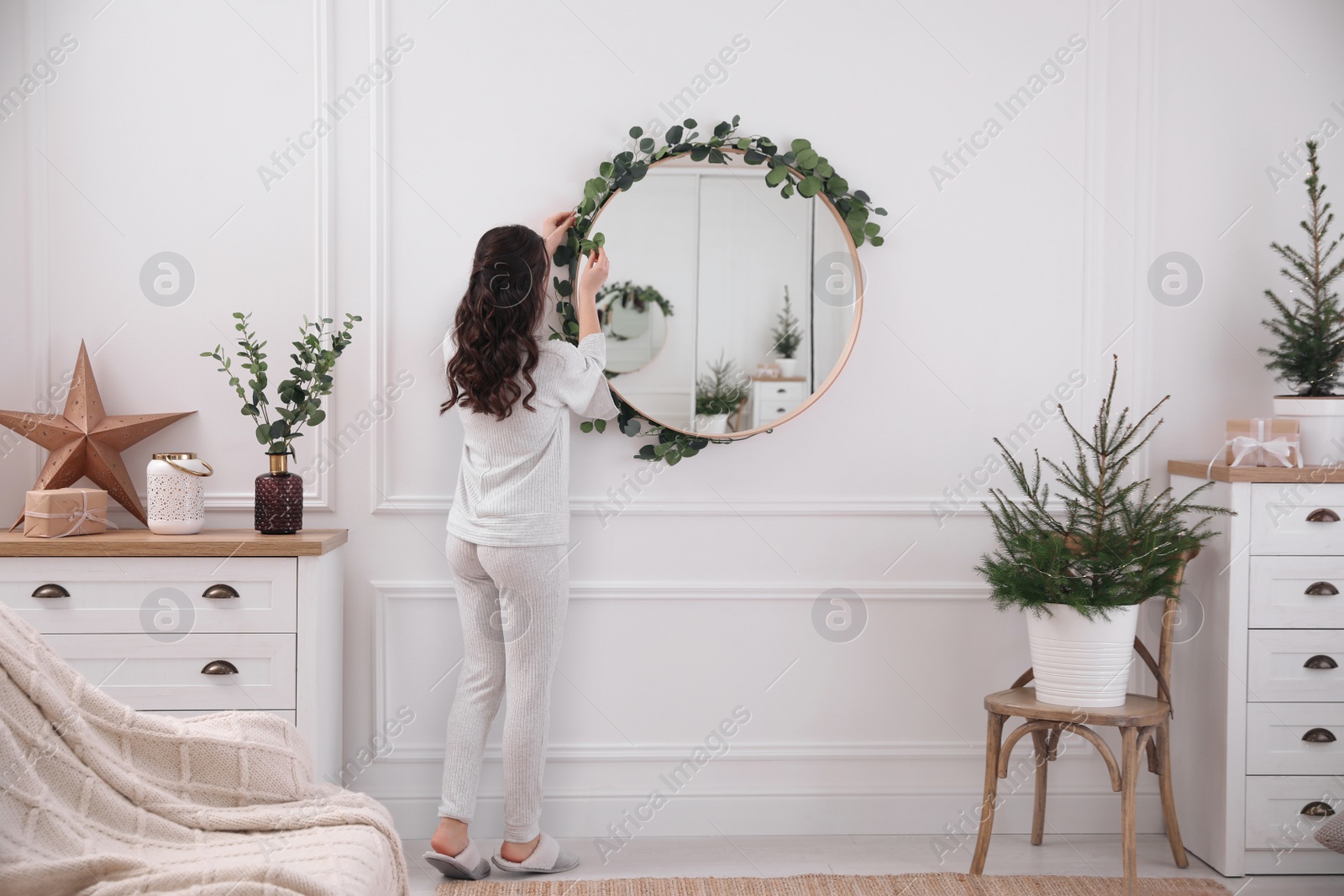 Photo of Woman decorating mirror with eucalyptus branches at home