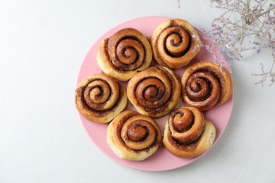 Many tasty cinnamon rolls on white table, top view