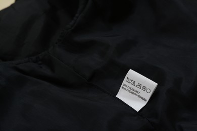 Clothing label on black garment, space for text