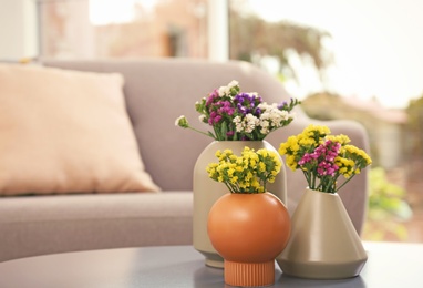 Photo of Beautiful flowers in vases as element of interior design on table. Space for text