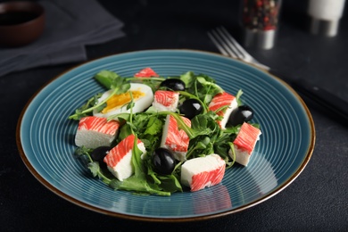 Photo of Delicious crab stick salad served on black table