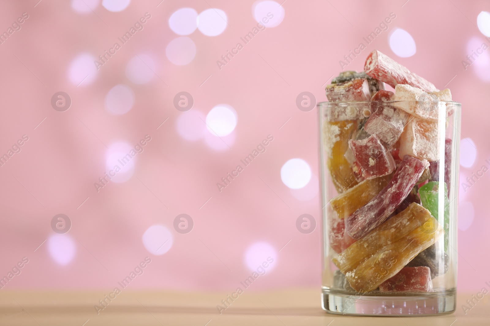 Photo of Delicious candies in glass on table against blurred background, closeup. Space for text