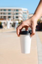 Woman holding takeaway coffee cup outdoors, closeup. Space for text