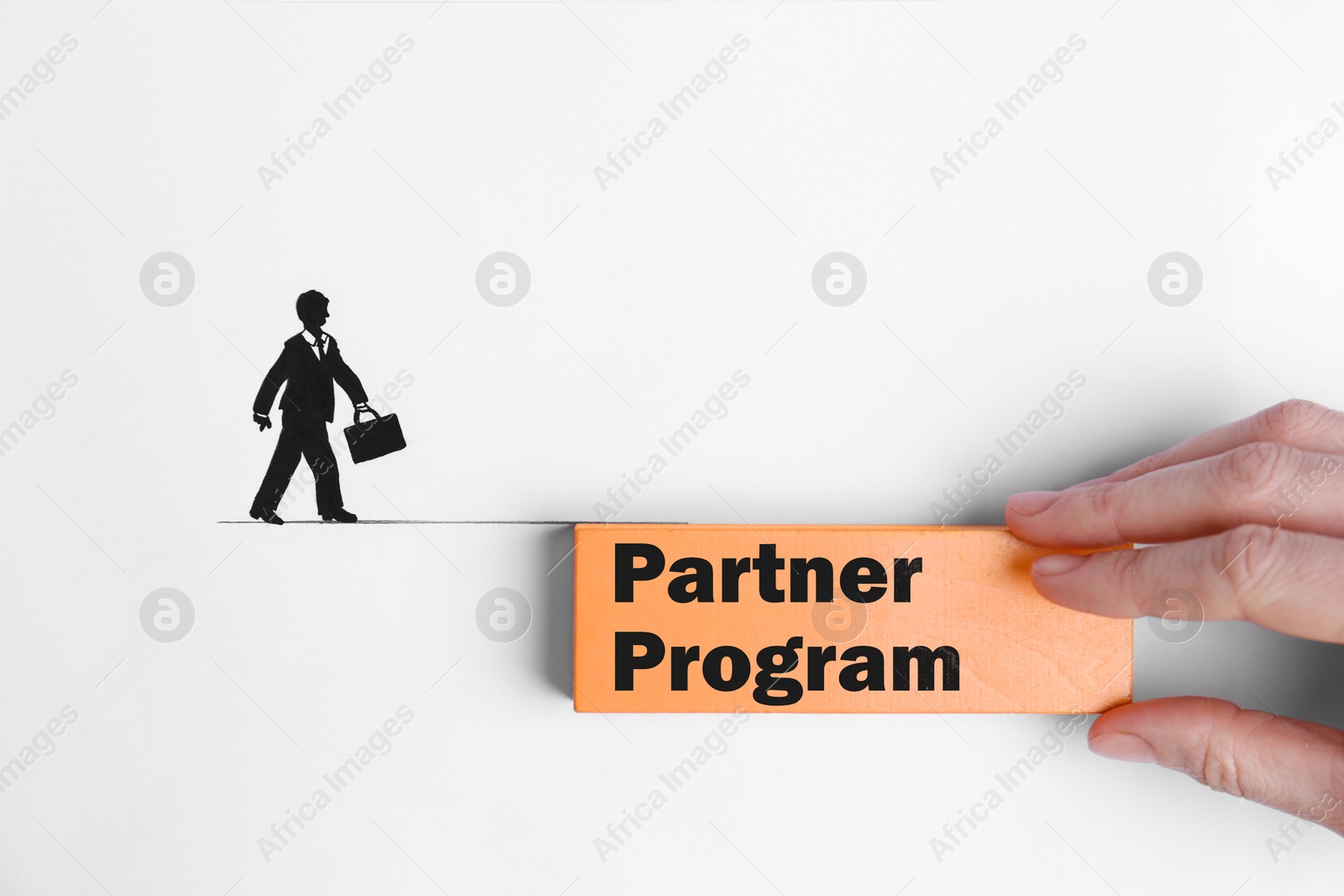 Image of Partner program. Woman holding wooden block near drawing of businessman walking on line, top view