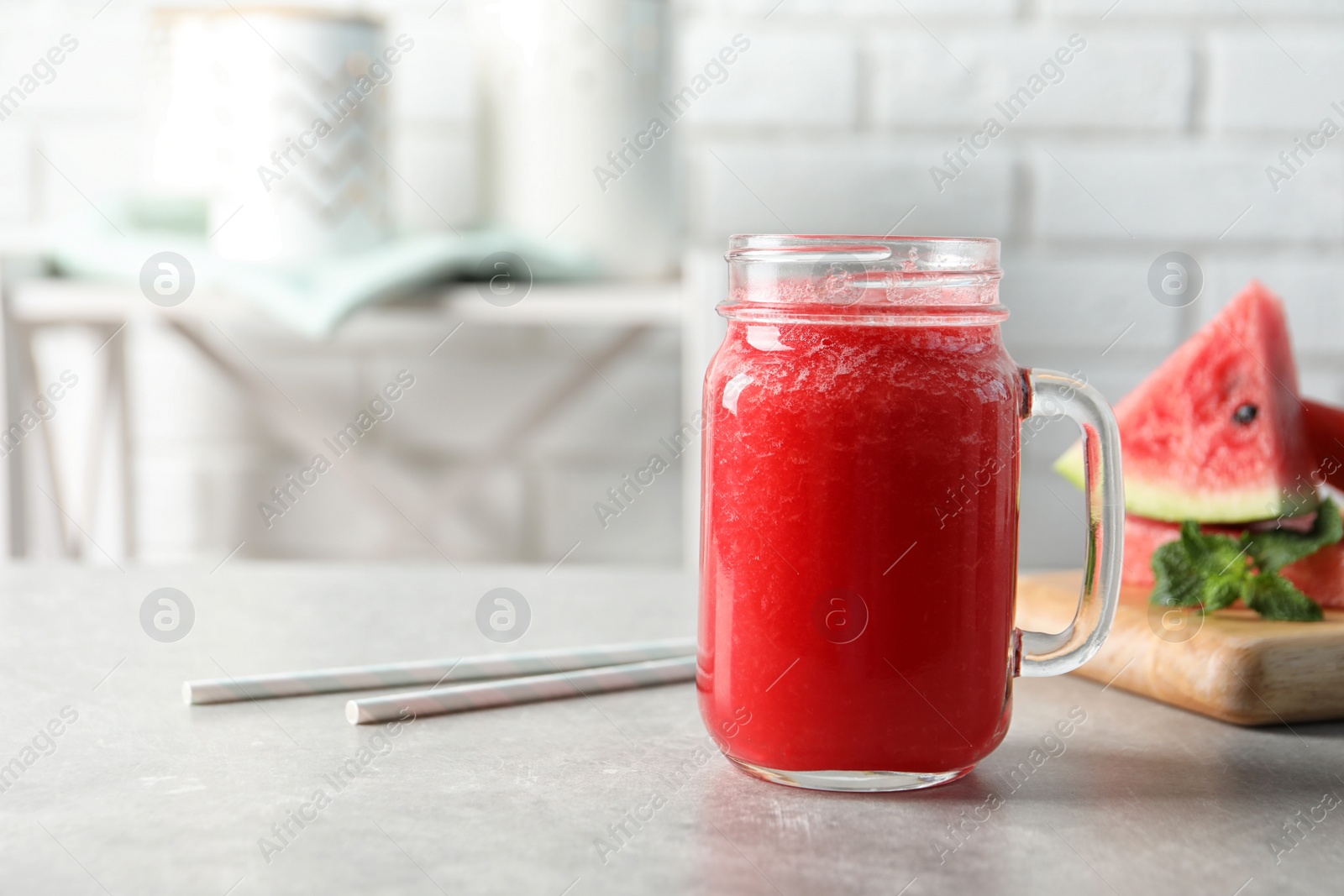 Photo of Tasty summer watermelon drink in mason jar on table against blurred background. Space for text