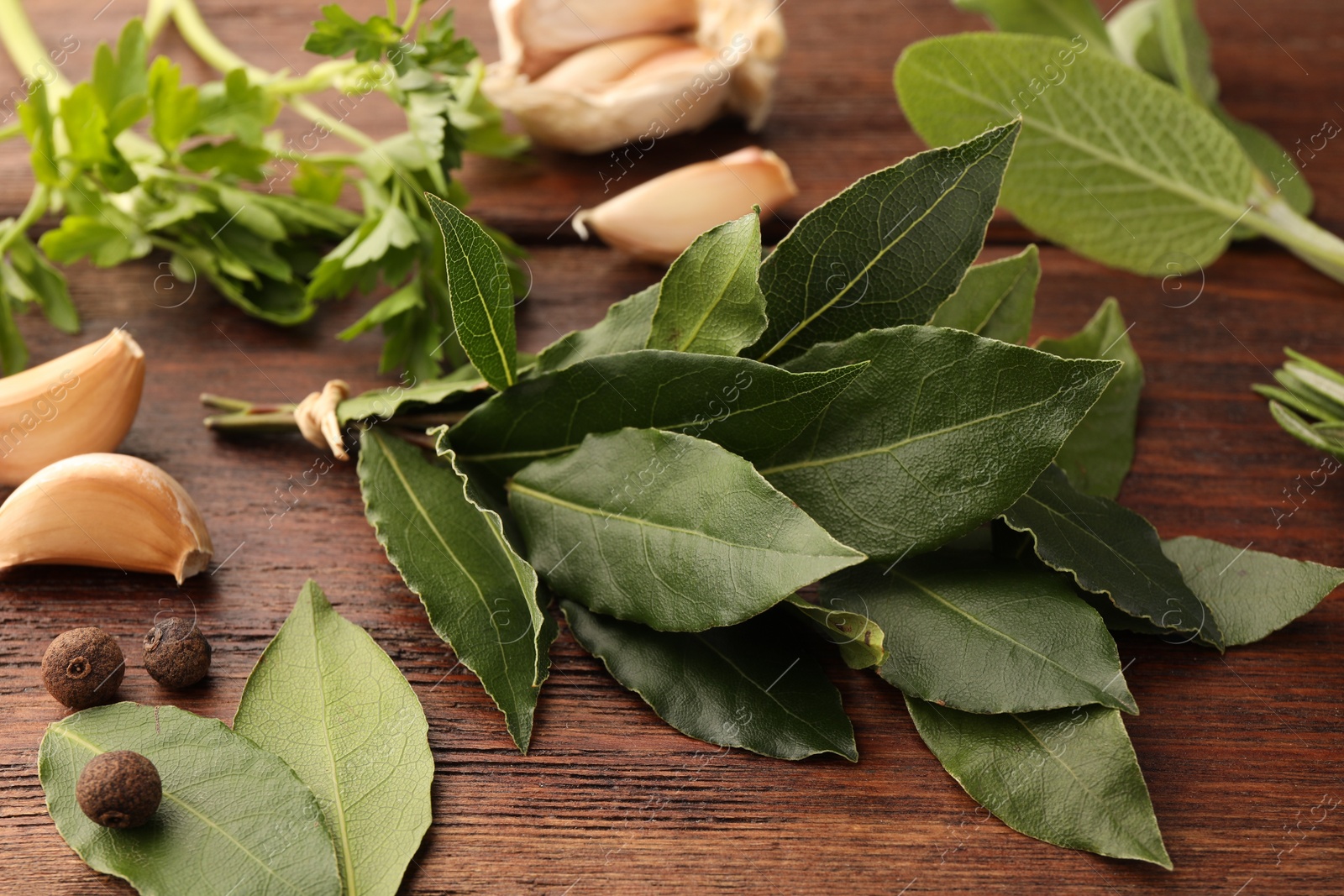 Photo of Aromatic fresh bay leaves and spices on wooden table, closeup