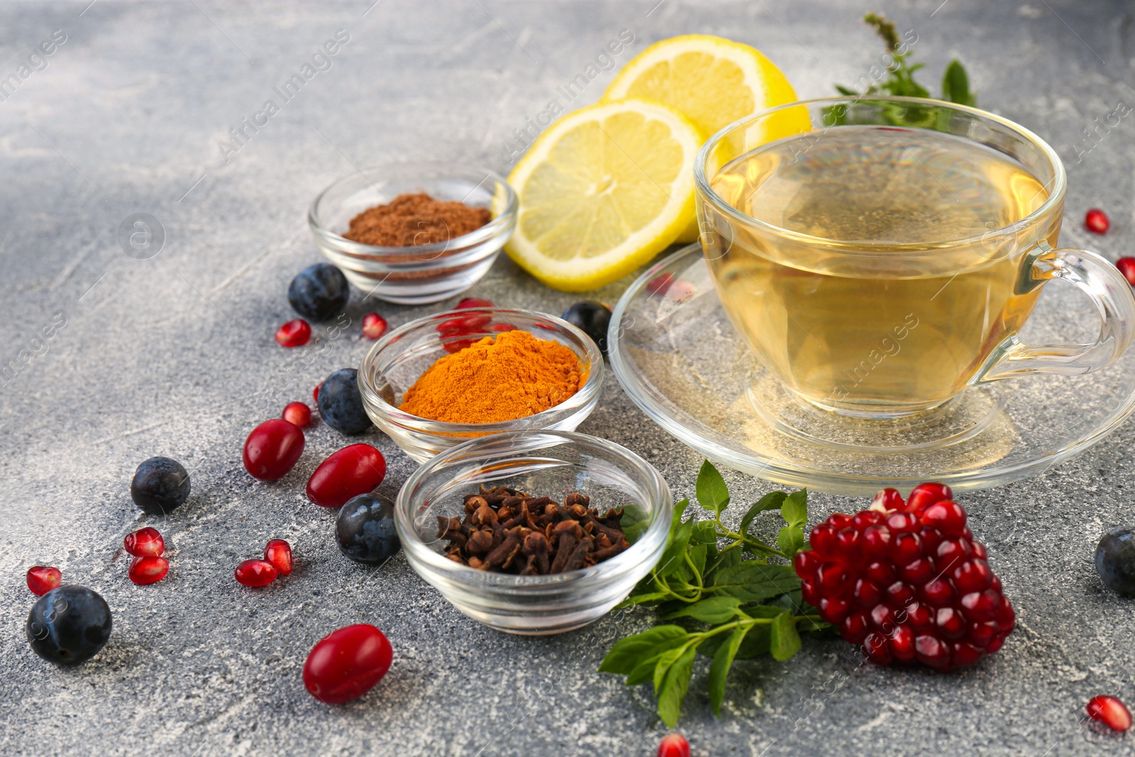 Photo of Cup with delicious immunity boosting tea and ingredients on grey table