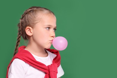 Photo of Girl blowing bubble gum on green background, space for text