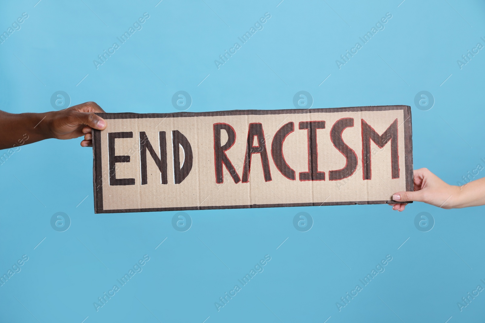 Photo of Woman and African American man holding sign with phrase End Racism on light blue background, closeup