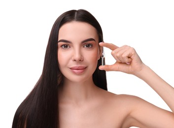 Photo of Beautiful young woman holding skincare ampoule on white background