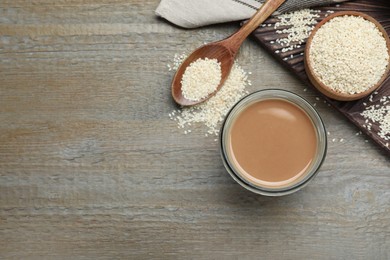 Photo of Jar of sesame paste and seeds on wooden table, flat lay. Space for text