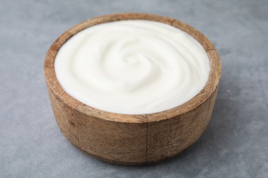 Delicious natural yogurt in bowl on grey table, closeup