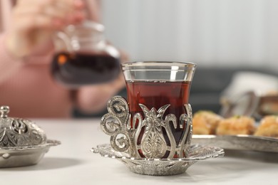 Woman having delicious Turkish tea at white table, selective focus